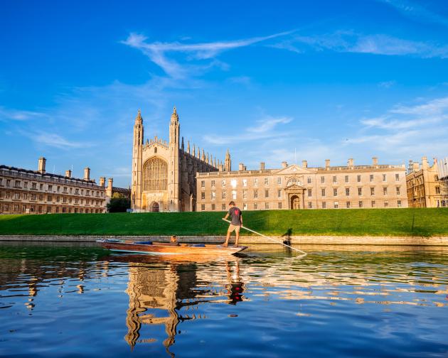 A landscape image of Kings College from across the Cam River. A group of people are punting down the river.