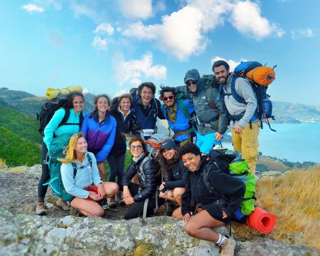 a group of students pose for a photo while on a hike through New Zealand's coast