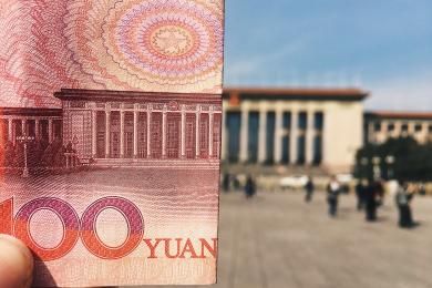Close up of 100 Yuan folded in half with the Great Hall of the People on Tiananmen Square in the background