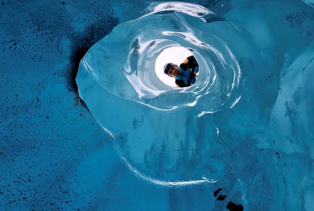 Person looking through a hole in a glacier.