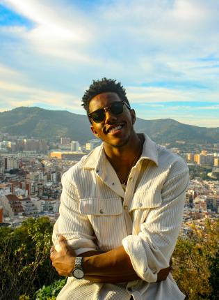 a male student standing in front of a mountainous Barcelona backdrop