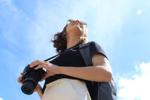 student standing holding camera and looking up at sky