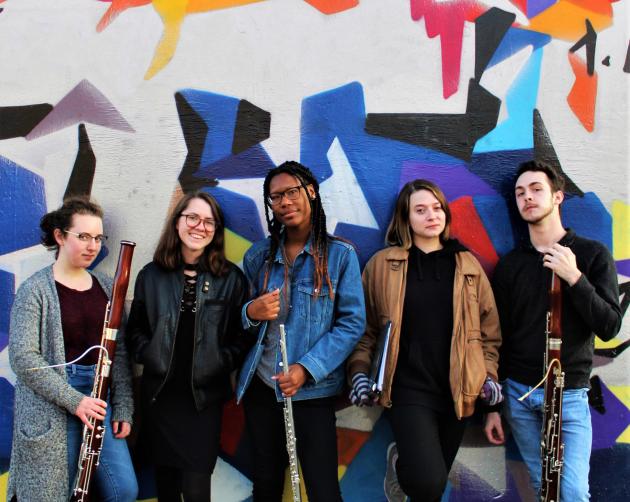 5 students standing with their instruments in front of a graffiti wall in Vienna