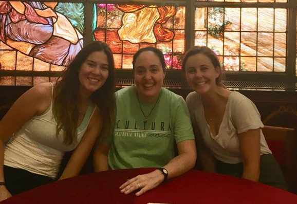 three women sitting at the table looking at the camera person