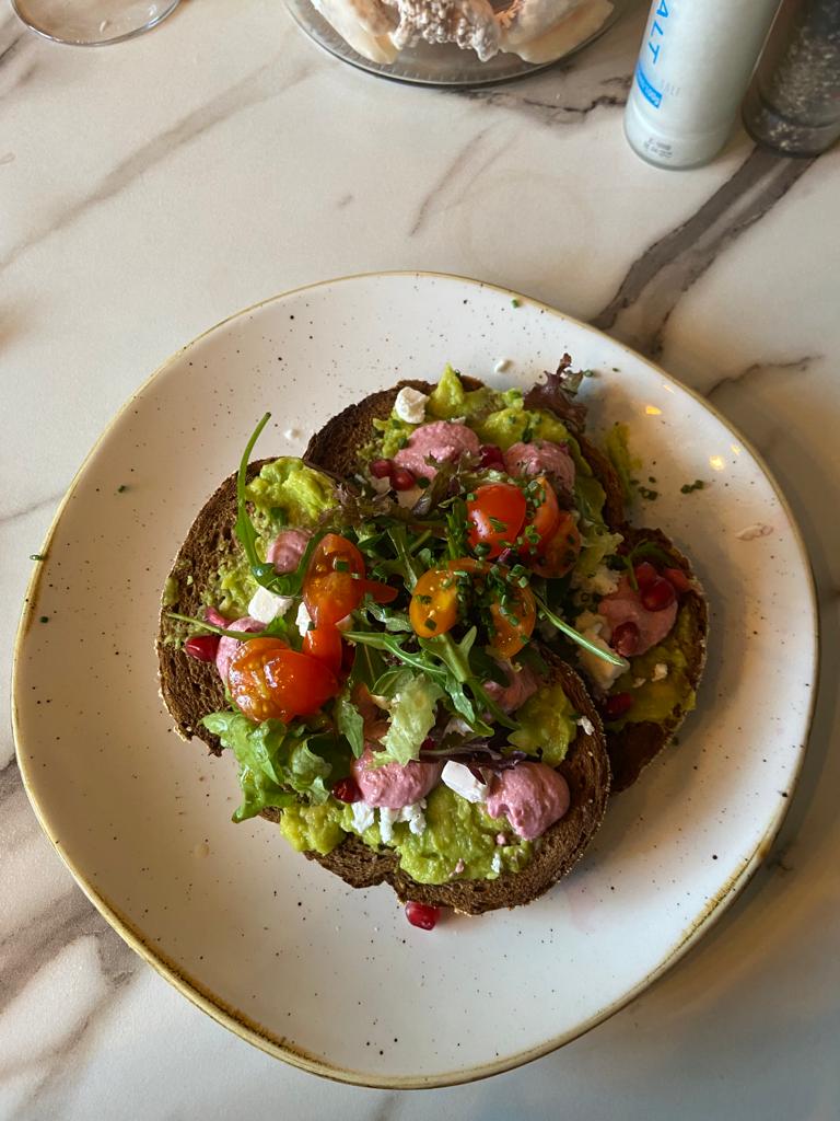 avocado toast with tomato, pickled radishes, feta, and avocado on whole wheat bread 