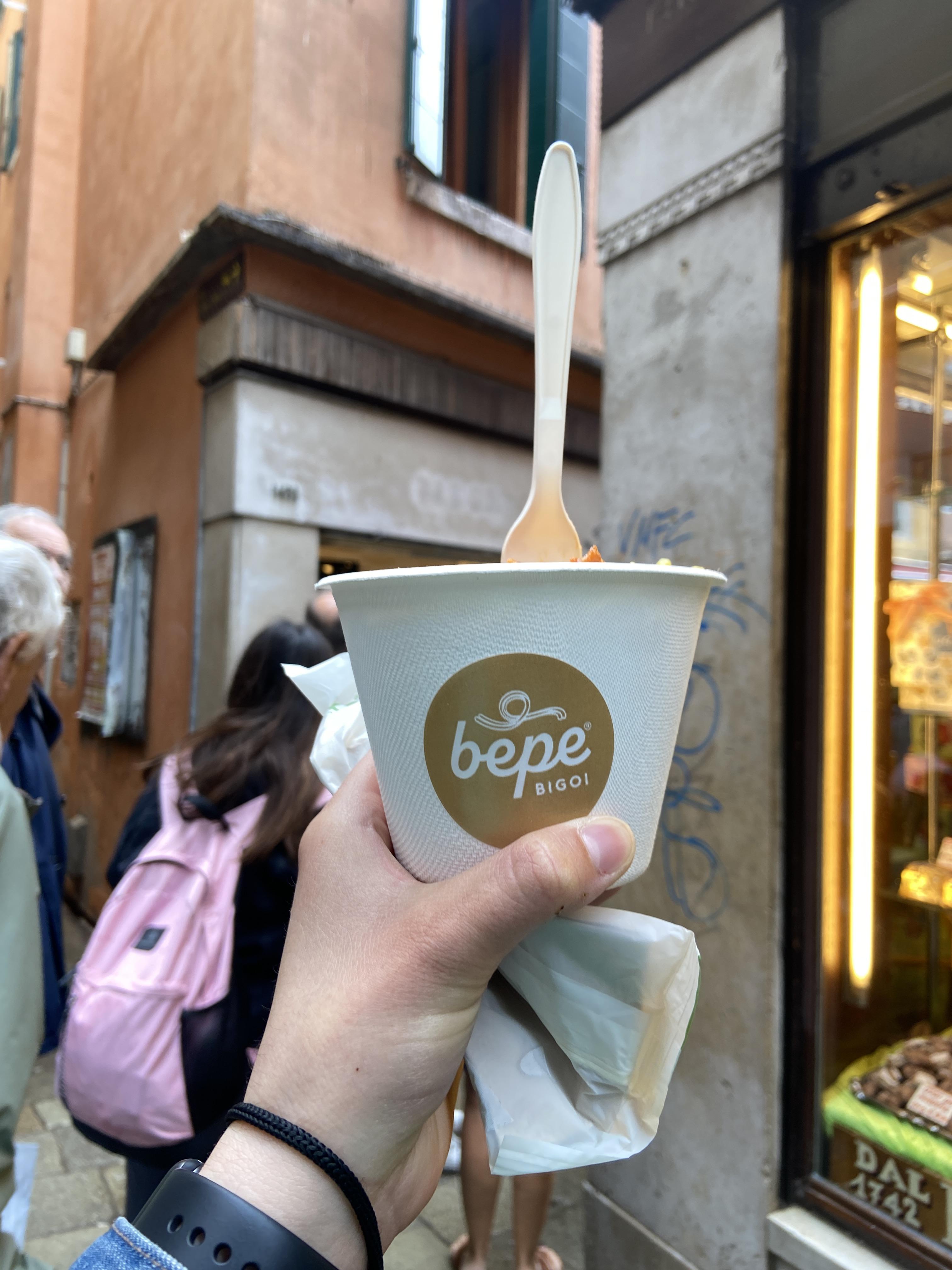 cup of pasta held in front of restaurant 