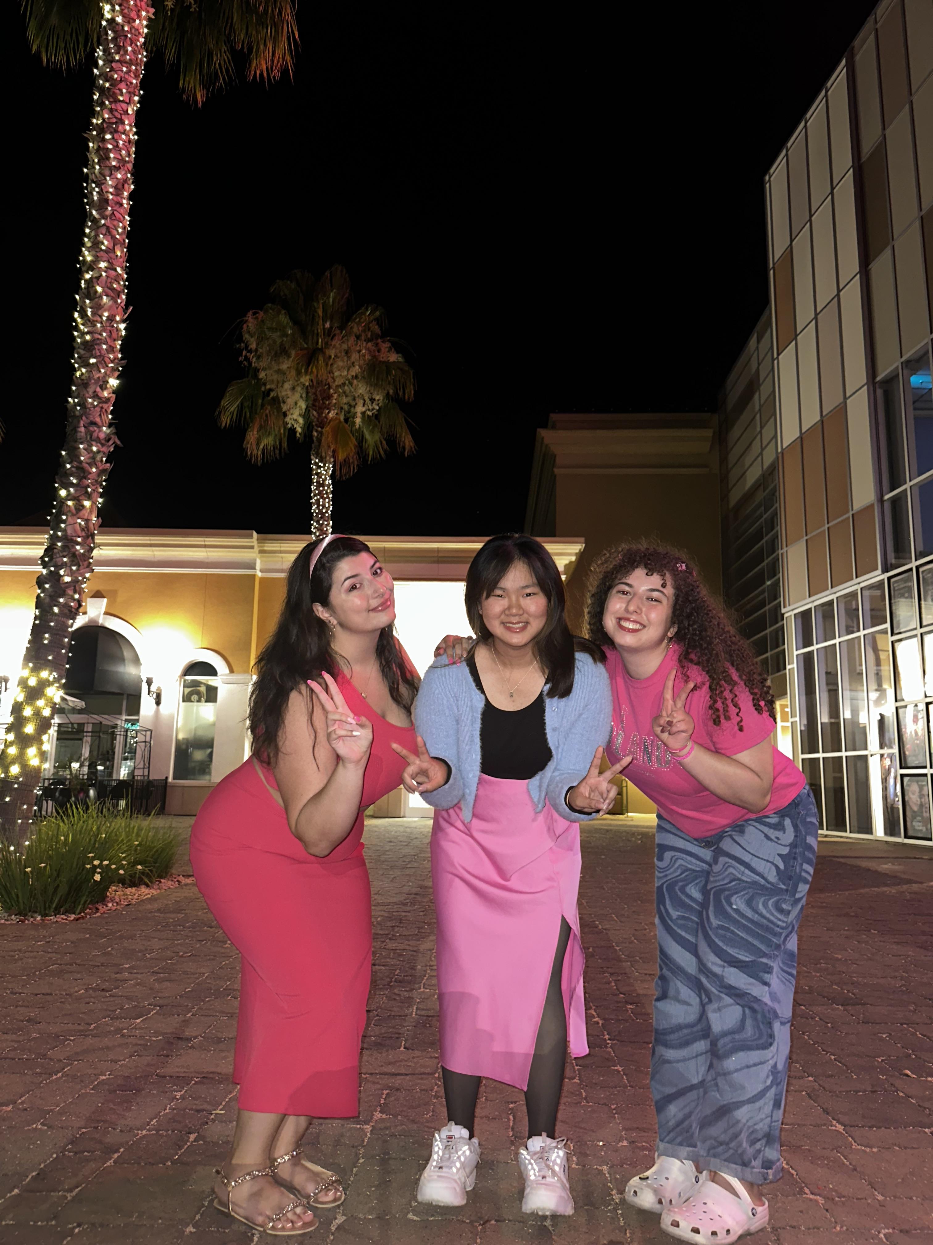 Three girls in a row smiling at the camera.