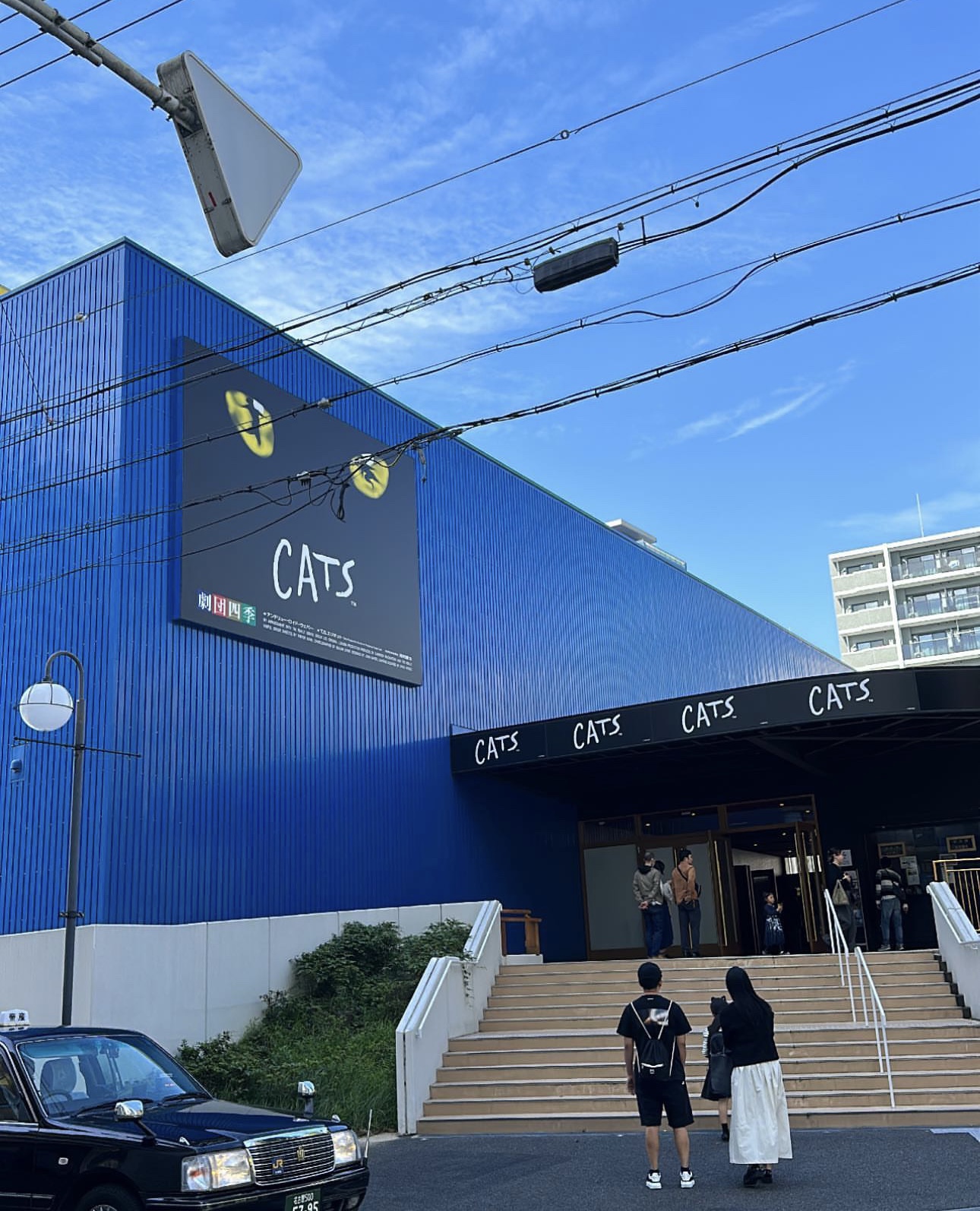 A blue building with a Cats advertising poster on the side.