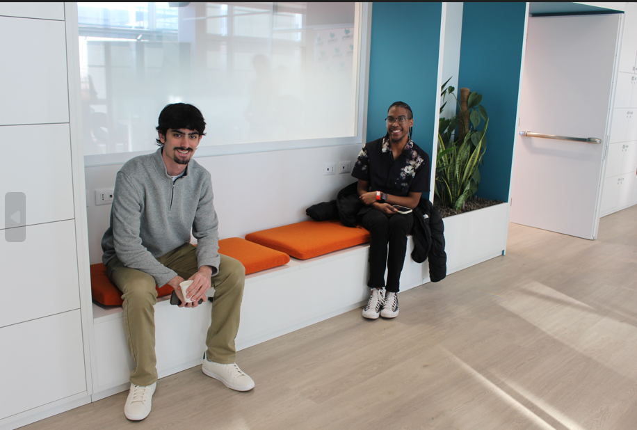 Two men sitting on a teal bench in a well-lit space