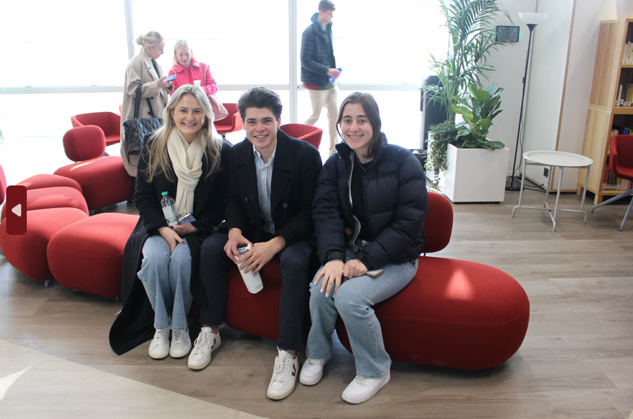 Three students sitting next to each other on a orange couch