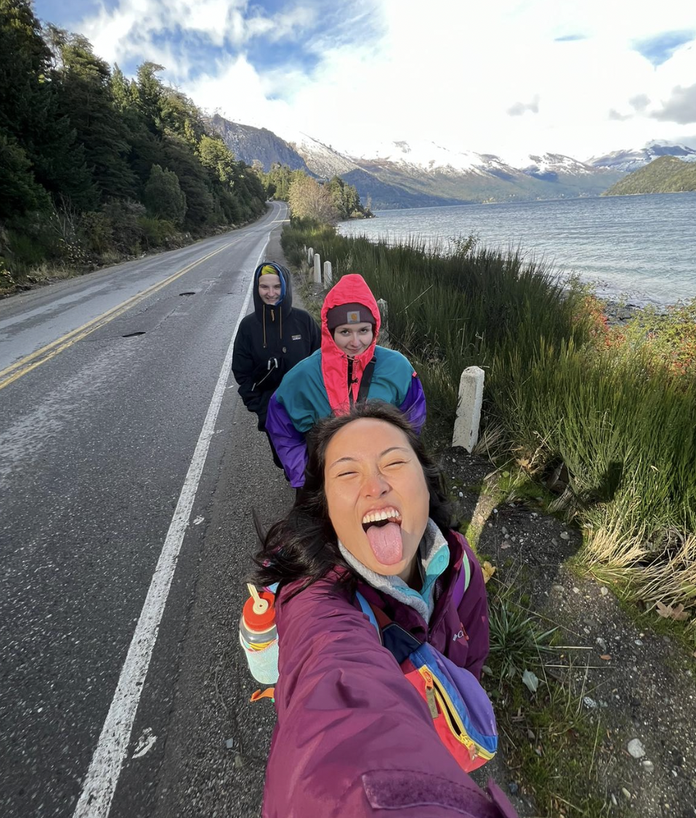 Three girls walking along the road overlooking mountains and a lake