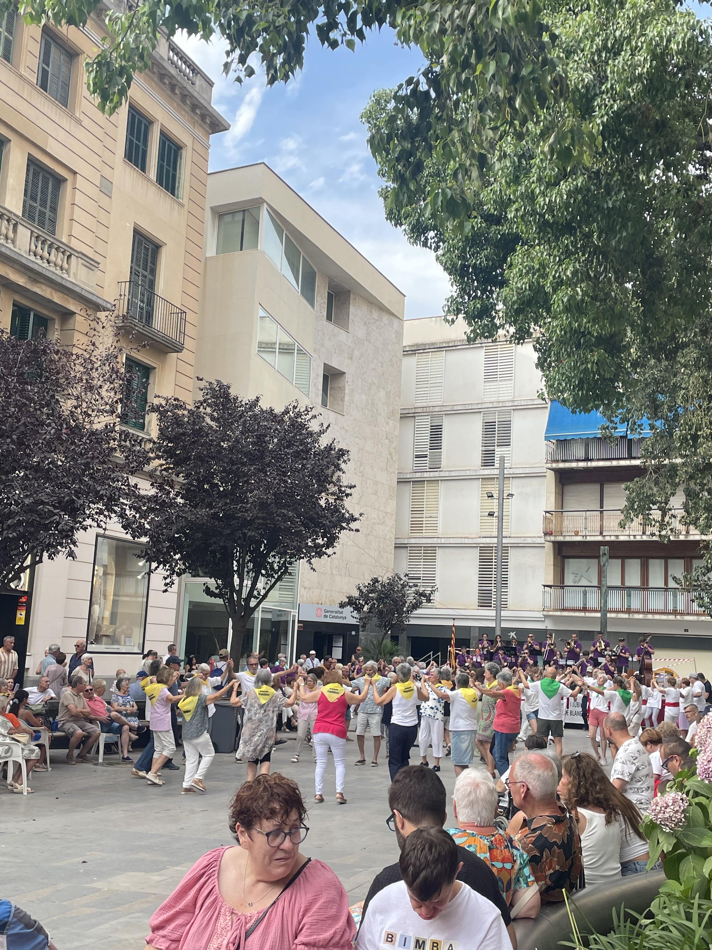 a group of older women hold hands as they dance in a circle in front of a band playing music