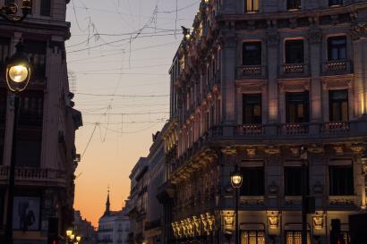 Between two white buildings lining a street in Madrid at night.