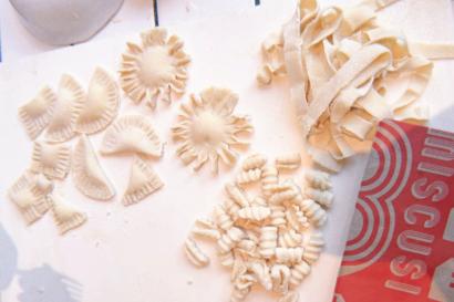 Tagiatelle, ravioli, and other types of handmade pasta rest on a table