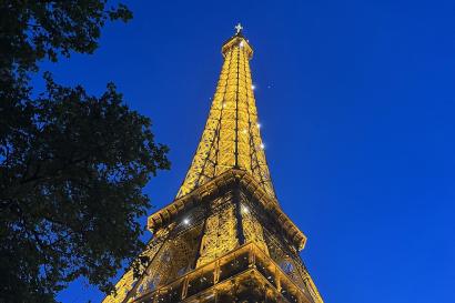 the sky is a bright blue as the sun is starting to set; the Eiffel tower is in view and is lit up