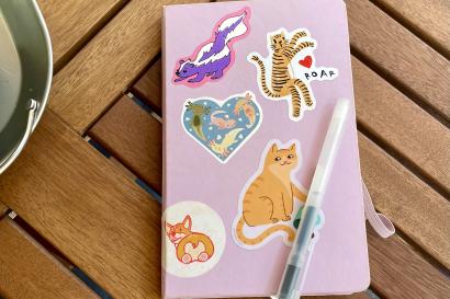 a purple journal with stickers on it sits on a wooden table.