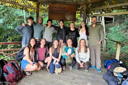 A group of 12 individuals with bags standing under a sign that says "Estación de Biodiversidad Tiputini". 