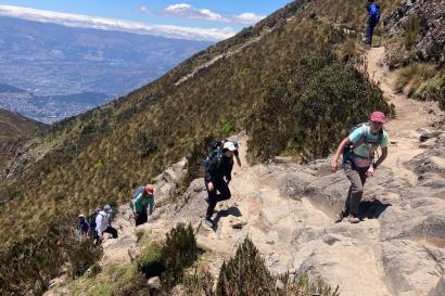 A few individuals hiking up the side of a mountain. 