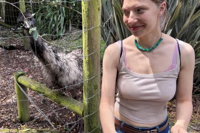 Girl standing by fence with an emu