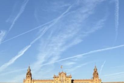 Large building with fountain in the middle and blue sky above.  