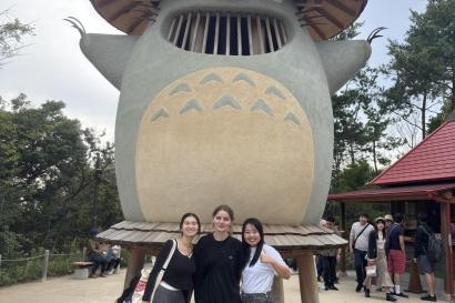 Me and two friends in front of a large Totoro statue