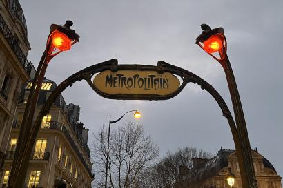 Metropolitan sign framed by two lamps and a cityscape background