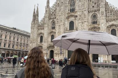 A photo of two girls' backs, as they look at the Duomo on a rainy day. 