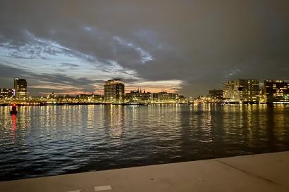 Looking from Amsterdam Noord, over a canal, to the skyline of Centraal around sunset.