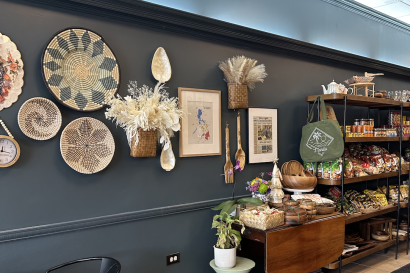 A picture of the wall at Lasa Filipino Cafe. Decorative weavings hang from the wall with shelves of plates and Filipino snacks along the wall.