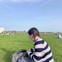 A girl looks through her bag in a wide field.