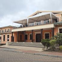 A peach-colored building with white trim, white columns, and a 2nd-floor balcony.