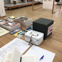 Book(s) open on check-in desk/bar; overseeing the exhibit 