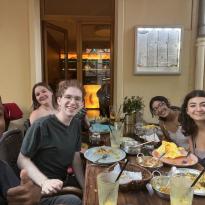 Selfie of six students sitting at a full table in a restaurant.