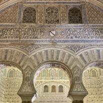 Three arches white in color with colums supporting them. Inscriptions on the wall of the arches 