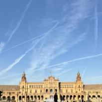 Large building with fountain in the middle and blue sky above.  