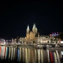 Big building in the middle of the picture with its lights reflecting on the water below