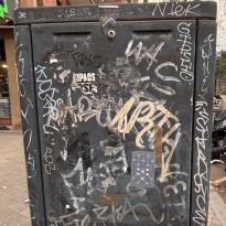 old metal box with graffiti in different colors and white stickers