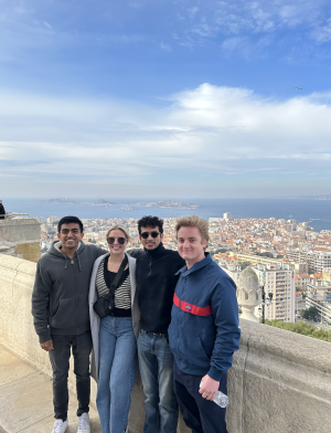 Four students at viewpoint in Nice, France - posing with city and ocean behind them 