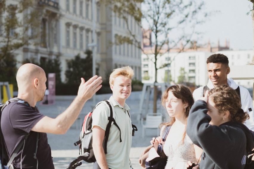 students standing near bicycles with building and trees in the background