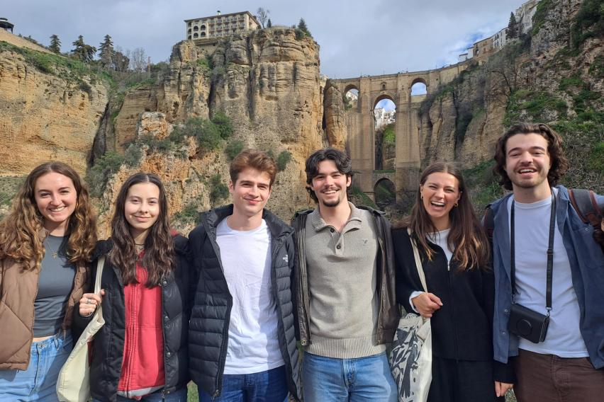 Six students smiling and standing in front of a large bridge in Ronda