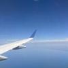 looking out a window of an airplane; one can see part of the airplane's wing and the blue sky