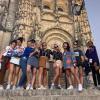 A group of high school study abroad students stand on the steps in front of an old cathedral in a rural town in Spain.