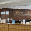 Front view of the Brandeis Student Financial Services reception desk, with a sign behind it reading 'Student Financial and Academic Services'