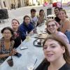 Selfie of a large group of students sitting outdoors at a long, white table 