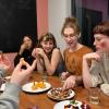 Candid photo of a group of students sitting around a long table. Some of the students are wearing Halloween costumes, and there are Halloween-themed snacks on the table. 