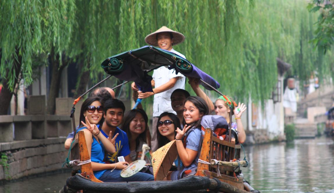 a group of students pose for a photo from a boat in a canal in Suzhou