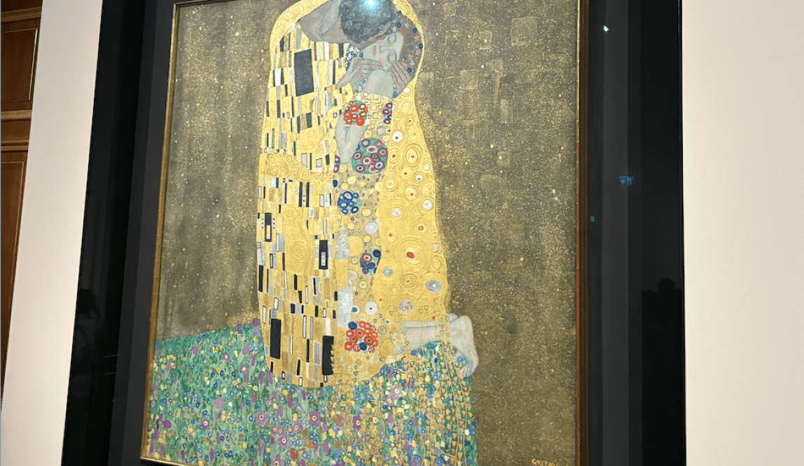 "The Kiss" By Gustav Klimt is a painting of a man and woman embracing each other in a golden covered blanket.