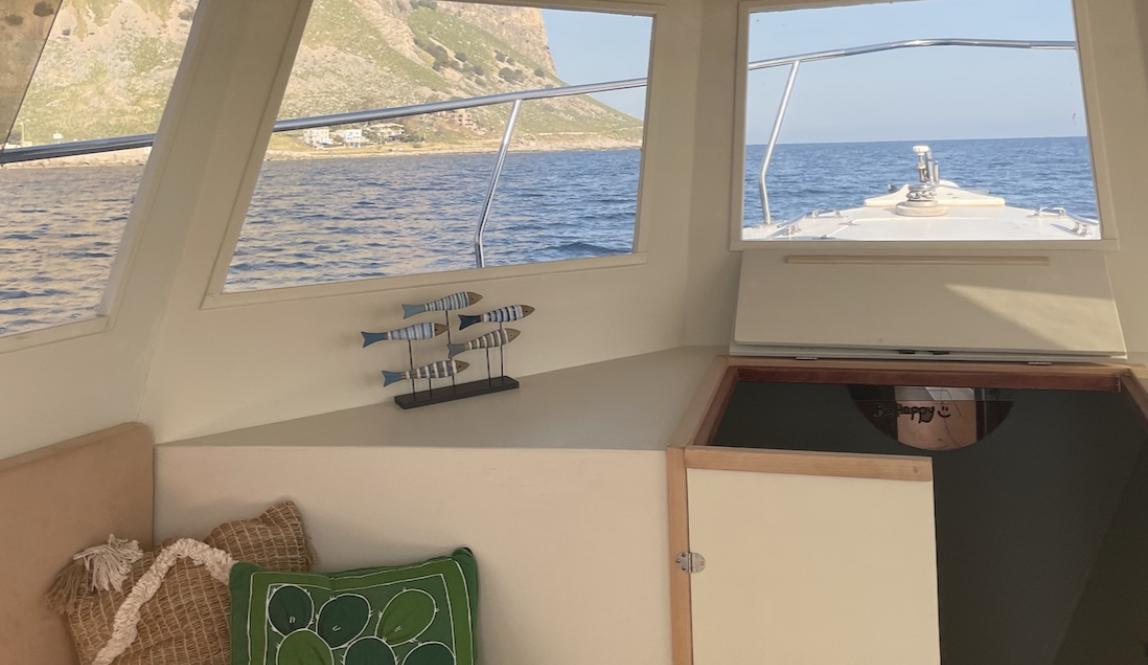 View of a bench inside a boat and out the window at the water