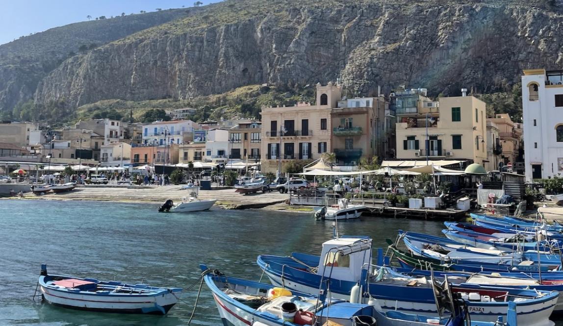 Mountain, boats, and colorful buildings from the dock in Mondello 