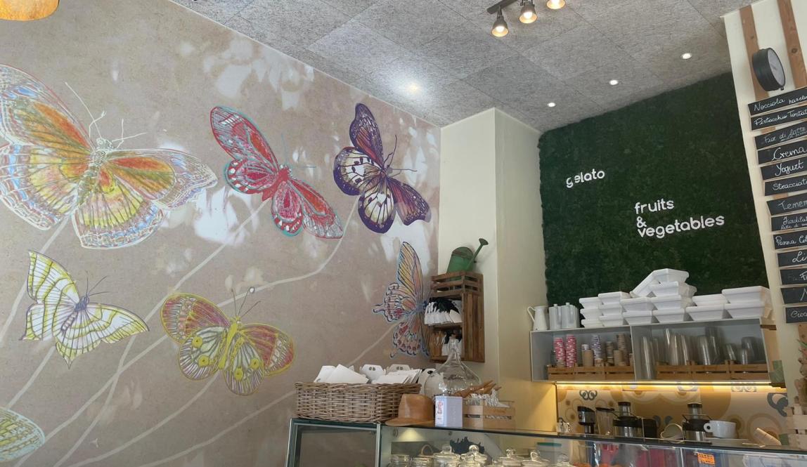 Butterflies are painted on one wall of this bakery, and to the right, the words "gelato" and "fruits and vegetables" are clearly visible